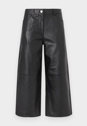 Culottes en cuir noir avec une coupe à jambes larges, poches frontales apparentes, fermeture par boutons et texture lisse et brillante.