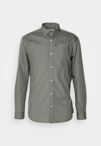 Camicia button-up verde oliva con maniche lunghe, colletto all'americana e bottoni bianchi. Realizzata in un tessuto liscio con una leggera lucentezza.