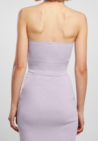 Abito a coste lilac con una forma aderente e design senza spalline, caratterizzato da una texture liscia e lunghezza fino a metà coscia.