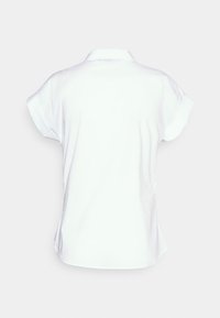 Lyhythihainen valkoinen paita, jossa on klassinen kaulus, sileä rakenne ja sivuhalkiot liikkumisen helpottamiseksi. Paidan design on puhdas ja minimalistinen.