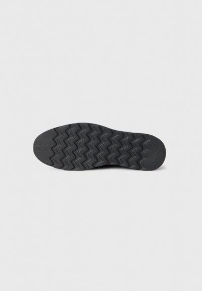Suola di scarpa in gomma nera con un modello a zigzag, forma piatta e superficie testurizzata per una presa sicura, adatta a diversi terreni.