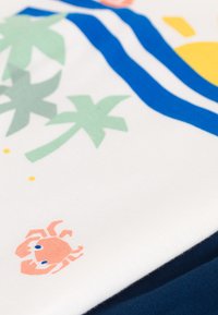 Weißer Stoff mit grünen Palmenblättern, blauen Streifen und einem Grafik eines rosa Krabben. Glatte Textur mit einem marineblauen Material darunter.