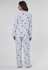 Pajama-Set aus Baumwolle mit hellblauem Hintergrund und vertikalen Streifen, verziert mit bunten Mustern von Pfannkuchen und Lutschern. Mit langen Ärmeln und Hosen.