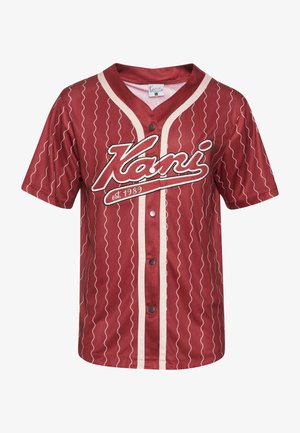 Červený baseballový dres s gombíkmi na prednej strane, zdobený bielymi vlnitými čiarami a veľkým bielym logom s textom "Kani est. 1989" na hrudi.