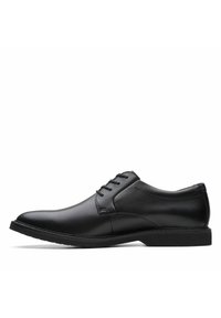 Zapato de vestir negro de cuero con textura suave, punta redonda y cinco ojales para cordones. Suela de goma negra de perfil bajo con detalles de costura sutiles.