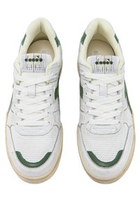 Zapatillas blancas con detalles verdes, tejido texturizado, diseño perforado en la puntera y suela de goma beige. Los cordones son blancos y la lengüeta tiene el logo.
