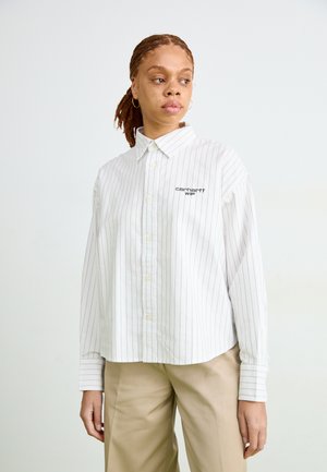Camisa blanca de botones con finas rayas verticales azul marino, con un corte relajado, cuello tipo polo y logo bordado en el pecho.