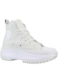 Zapatilla alta blanca de cuero con costuras en tono, un parche redondo con el logo y una suela gruesa de goma blanca con un dibujo de relieve irregular.