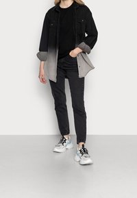 Camicia di jeans con gradienti in nero e grigio, maglione nero, jeans neri e scarpe con dettagli bianchi e azzurro chiaro. Vestibilità casual e design moderno.