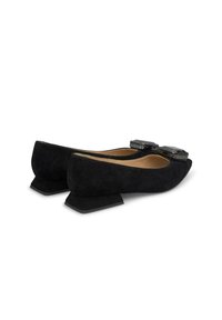 Ballerines en daim noir avec des talons bloc angulaires, présentant deux éléments décoratifs en matériau brillant dans la zone des orteils.