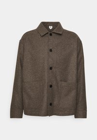 Veste en laine marron avec col, boutons noirs et deux poches avant, présentant un tissu texturé et une coupe décontractée.