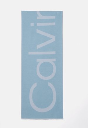 Tapis rectangulaire bleu clair avec un grand texte blanc vertical indiquant "Calvin" sur un fond blanc uni.