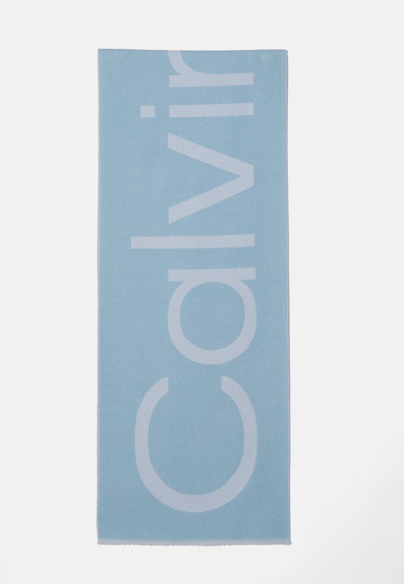 Tapis rectangulaire bleu clair avec un grand texte blanc vertical indiquant "Calvin" sur un fond blanc uni.