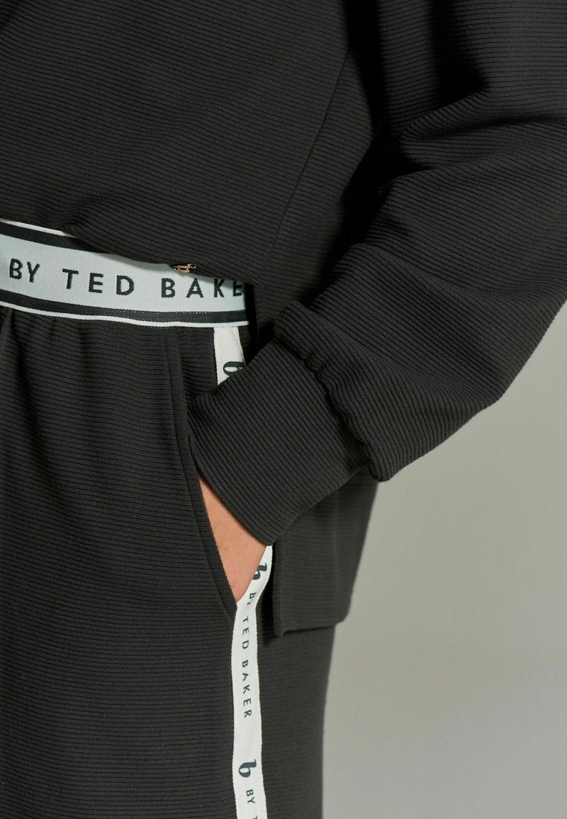 Zwarte geribde sweatshirt met een relaxte pasvorm, elastische manchetten en een zak met een merkgebonden wit en zwarte trekkoord in de taille.