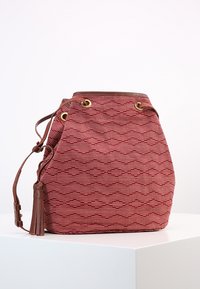 Rød mønstret bucket-taske med en tekstureret stofkrop, brune læderdetaljer, gyldne nitter og en kvast som dekoration.