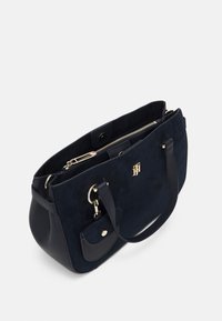 Borsa a mano in suede blu navy con dettagli in pelle texturizzata, doppi manici superiori e chiusura con zip. Presenta una piccola tasca frontale con chiusura a scatto.
