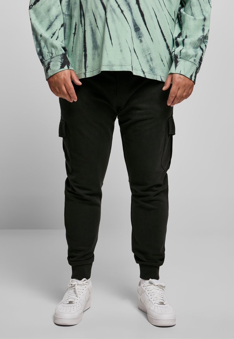 Zwarte cargojoggingbroeken met zijzakken, gecombineerd met witte sneakers. De bovenkant is een mintgroene tie-dye langemouwen T-shirt met zwarte accenten.