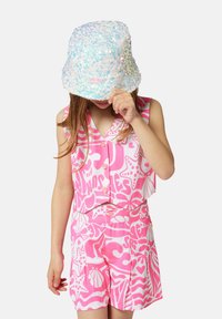 Haut sans manches rose et short à motifs blancs audacieux ; associé à un chapeau seau pastel scintillant. Le matériau semble léger.