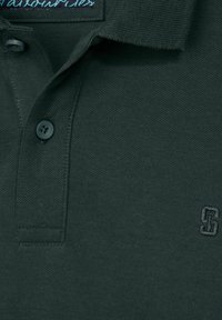 Polo shirt vert foncé en coton texturé, doté d'un col replié, de deux boutons et d'un logo brodé discret sur la poitrine.
