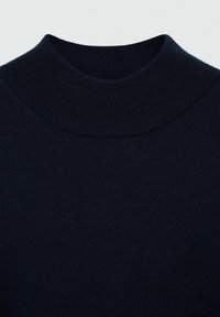 Pulover tricotat de un albastru închis, cu guler înalt și ribetat, având o textură netedă și moale. Designul este simplu și modern, fără modele vizibile.