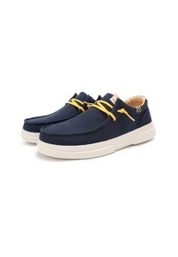 Zapatos de lona azul marino con suela de goma blanca, que presentan cordones amarillos y un forro naranja estampado. Diseño simple y redondeado con acentos mínimos.