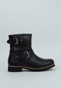 Bota de cuero negro con detalle de hebilla, altura al tobillo, suela robusta y textura suave. Presenta una cremallera lateral y costuras en contraste color marrón.