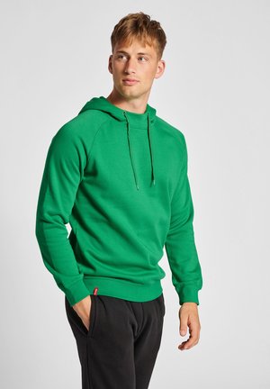 Groene hoodie van zacht materiaal, met een trekkoord capuchon, ribgebreide manchetten en zoom, gedragen met zwarte broek. Eenvoudig, atletisch ontwerp.