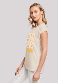 Beige cotton T-shirt with short sleeves, featuring a floral design in yellow and white with the word "Summer" in bold yellow text.