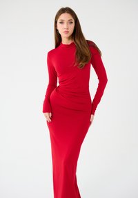 Abito lungo rosso con maniche lunghe, dal taglio aderente, realizzato in tessuto morbido e elasticizzato, con scollatura a cowl e dettagli arricciati in vita.