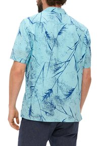 Camisa de manga corta en tejido azul claro con patrones florales azul oscuro y un ajuste relajado. Textura suave y diseño con cuello.