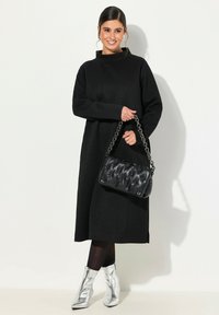 Černé strukturované midi šaty s vysokým límcem, spojené s černou prošívanou kabelkou a stříbrnými kotníkovými botami. Elegantní, minimalistický outfit.