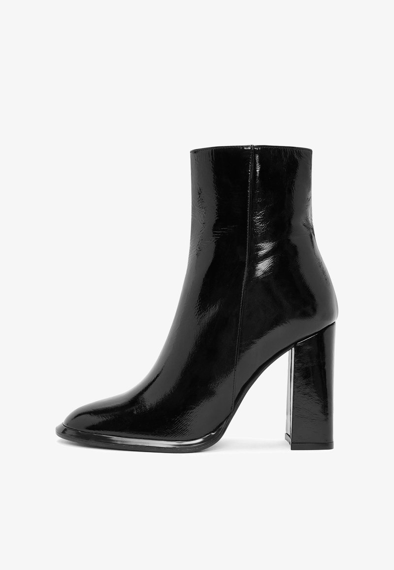 Bottine en cuir verni noir au design épuré, avec un bout pointu et un talon épais transparent, présentant une texture lisse et brillante.
