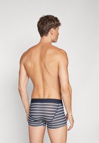 Herren Badeshorts aus weichem Stoff, mit einem navyfarbenen Grundton und horizontalen weißen Streifen, elastischem Bund und figurbetontem Schnitt.