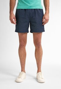 Pánské námořnické plavky s opakujícím se vzorem mušlí, vyrobené z lehkého materiálu. Obsahují elastický pas a boční kapsy.