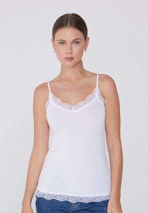 Camiseta blanca sin mangas con tirantes finos, que presenta un acabado de encaje con bordes en el escote y el dobladillo inferior. Material de algodón suave, forma ajustada.