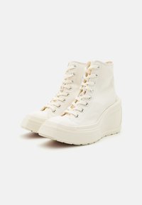 Høyt topsko i off-white lerret med metallhull, med en grov plattformsåle og rund tådesign.