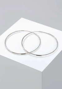 Pendientes en forma de aro de metal plateado, de forma circular, con textura suave, que exhiben un acabado pulido con un diseño delgado y elegante.