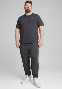 Mørkegrå kortærmet t-shirt med logo og matchende joggers. Sættet har en blød tekstur, afslappet pasform og hvide sneakers.
