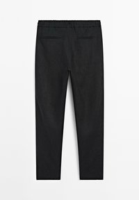 Zwarte taps toelopende broek met elastische tailleband en twee achterzakken, platgelegd op een witte achtergrond.