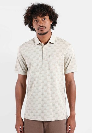 Polo beige avec un motif discret d'arbres, manches courtes et patte de boutonnage. Comprend une poche poitrine et un tissu doux et texturé.
