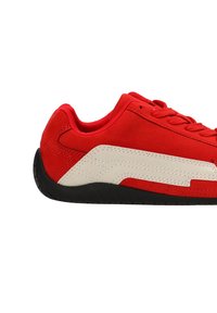 Zapatillas de ante rojo con una franja lateral blanca sintética, suela de goma negra y diseño tradicional de cordones.