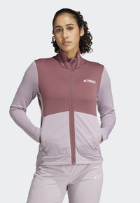 Fleecedžempera s patentnim zatvaračem, s dizajnom u boji u svijetloplavoj i ružičastoj. Izrađen od teksturirane tkanine s bočnim džepovima. Prisutni TERREX logo.