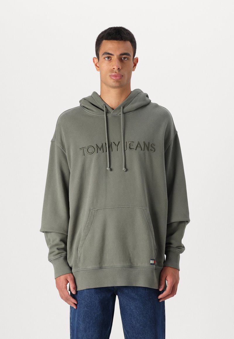 Felpa grigia in cotone con tasca a marsupio, dotata di un logo ricamato "TOMMY JEANS". Ha un cappuccio con coulisse e polsini a coste.