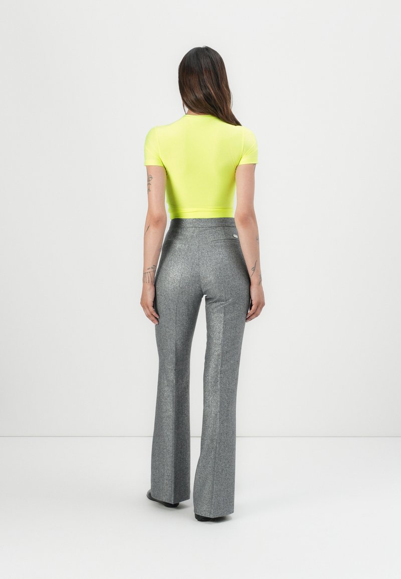 Top de manga corta amarillo neón combinado con pantalones grises de tiro alto y acampanados, con textura. Tejido suave con un brillo sutil.