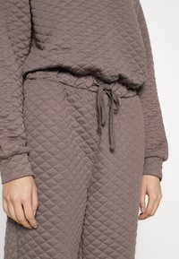 Grå quiltad lounge-set, med ett strukturerat mönster, elastiskt midjeband med dragsko och ribbade muddar på ärmarna.