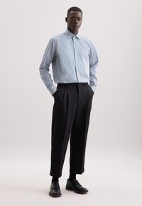 Lichtblauw en wit gestreept overhemd met knopen, gecombineerd met zwarte geplooide broek en zwarte leren schoenen. Soepele stof, tailored fit.