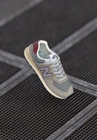 Sneaker in rete grigio e suede con accenti bordeaux, suola in gomma e lacci bianchi. Presenta un grande logo 'N' sul lato.