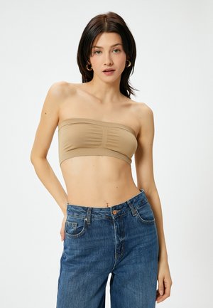 Beige strapless top med en glat tekstur, der har et subtilt sammenfoldet design foran, parret med højtaljede blå denim jeans.