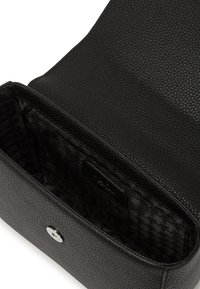 Borsa in pelle nera con texture, dotata di chiusura con zip e foderata internamente con una finitura liscia e un motivo sottile, accentuata da dettagli in metallo argentato.