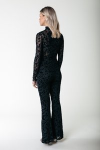 Jumpsuit s uzorkom crnog leoparda s prilagođenim, dugim rukavima i širom nogavicama. Izrađen od prozirnog, strukturiranog materijala s visokim izrezom.